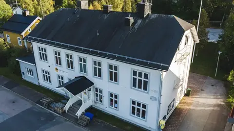 Gamla Engelmarks-huset i Jokkmokk med vit fasad och  tre våningar. Fotad utifrån en sommarkväll. Foto: CJ Utsi