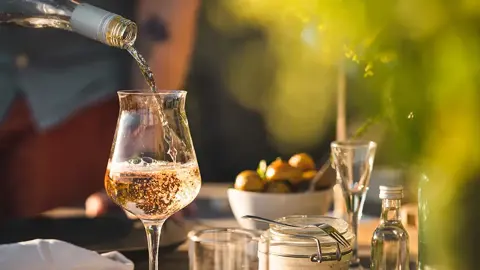 Vitt vin hälls upp i ett vinglas. Foto.