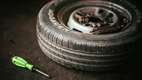 Ett däck och skruvmejsel som ligger på ett betonggolv. Foto.
